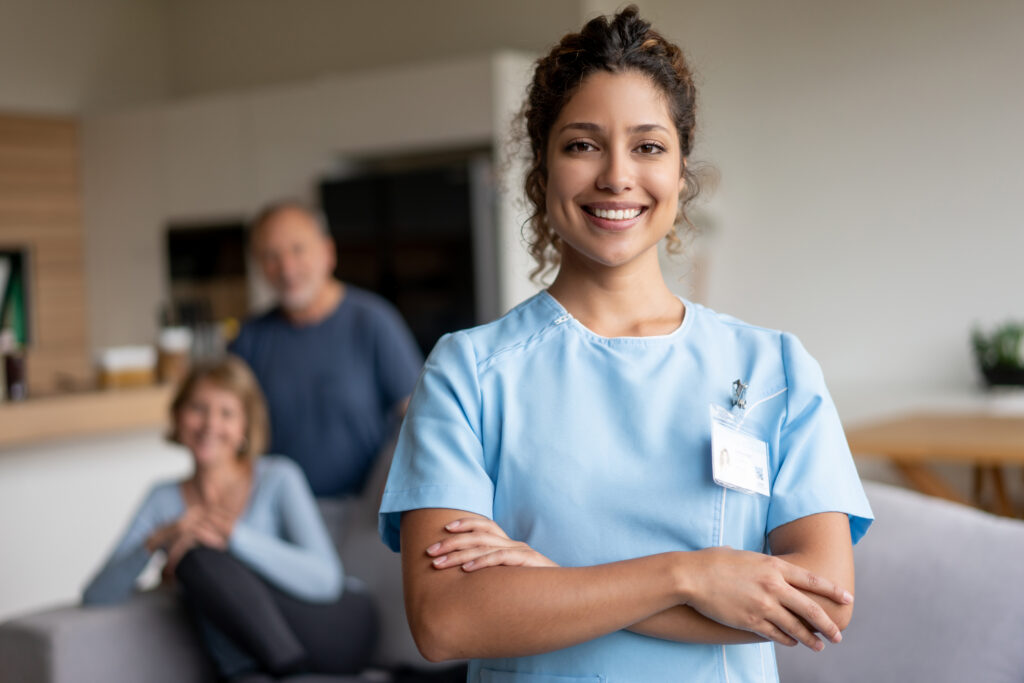 Smiling home caregiver in uniform in a client’s living room