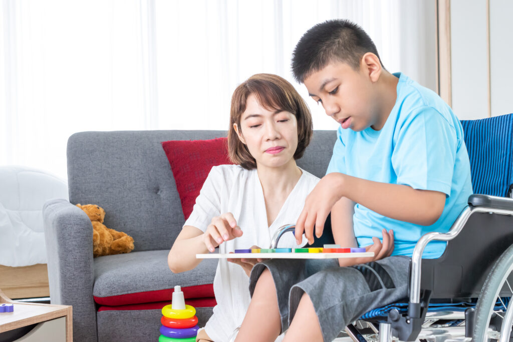Caregiver playing with a child in a wheelchair at home